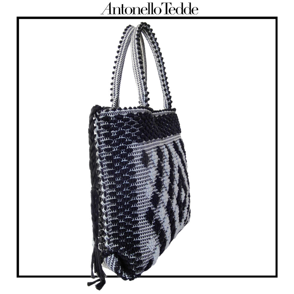 SIDE VIEW of Sustainable black and grey tote bag featuring a unique pattern of small diamonds forming a larger diamond, crafted using authentic Sardinian hand-weaving techniques in ethically managed factories. This eco-conscious tote bag combines contemporary design with traditional craftsmanship, offering a stylish accessory that embodies sustainability and cultural heritage.