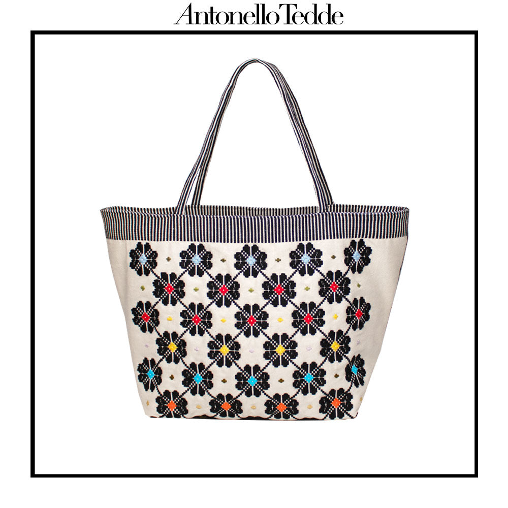 Front view of a black and white tote bag with a daisy pattern. Main view of our Sustainable tote - summer bag - luxury handbag - handwoven made in Italy by hand - timeless individualistic fashion • eco-friendly fashion • socially responsible, lasting fashion.