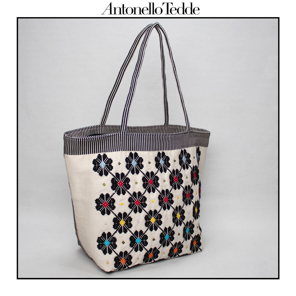 Side view of a black and white tote bag with a daisies pattern. Main view of our Sustainable tote - summer bag - luxury handbag - handwoven made in Italy by hand - timeless individualistic fashion • eco-friendly fashion • socially responsible, lasting fashion.