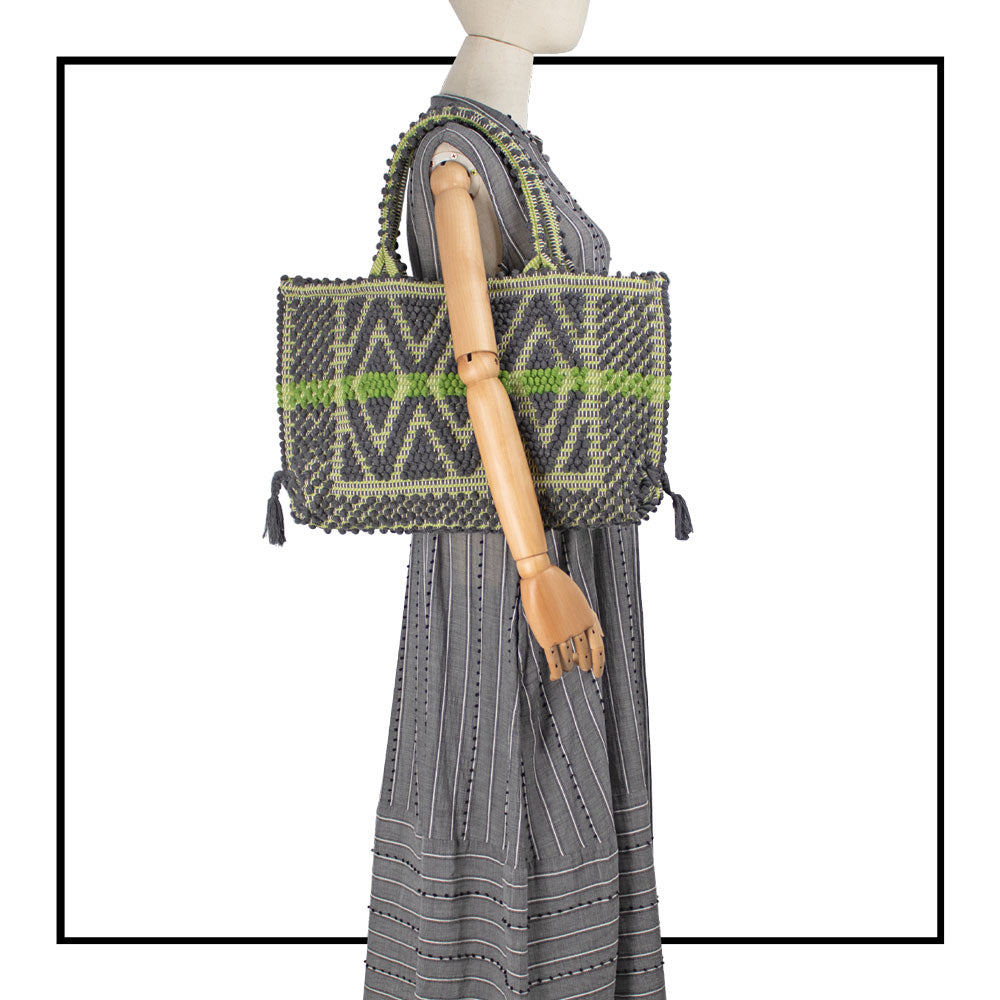 Gray sleeveless dress with a standing collar, crafted from 100% Khadi cotton handwoven in India and made in Italy, featuring a flowing design with pom detail and with hidden pockets and a matching belt for versatile styling.