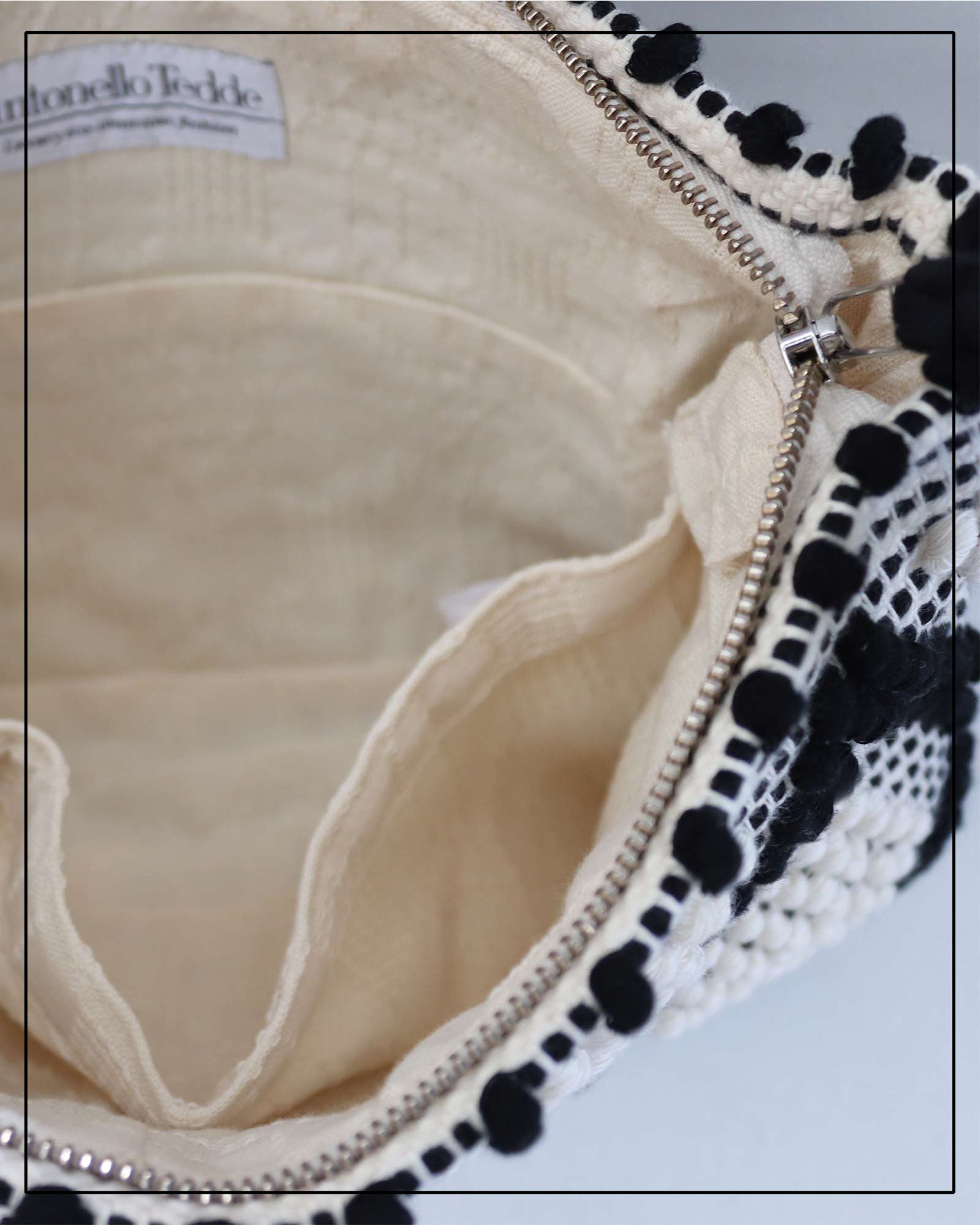 Antonello Tedde cream and white  clutch bag with multiple diamond patterns and pom-pom details on a white background - opening view