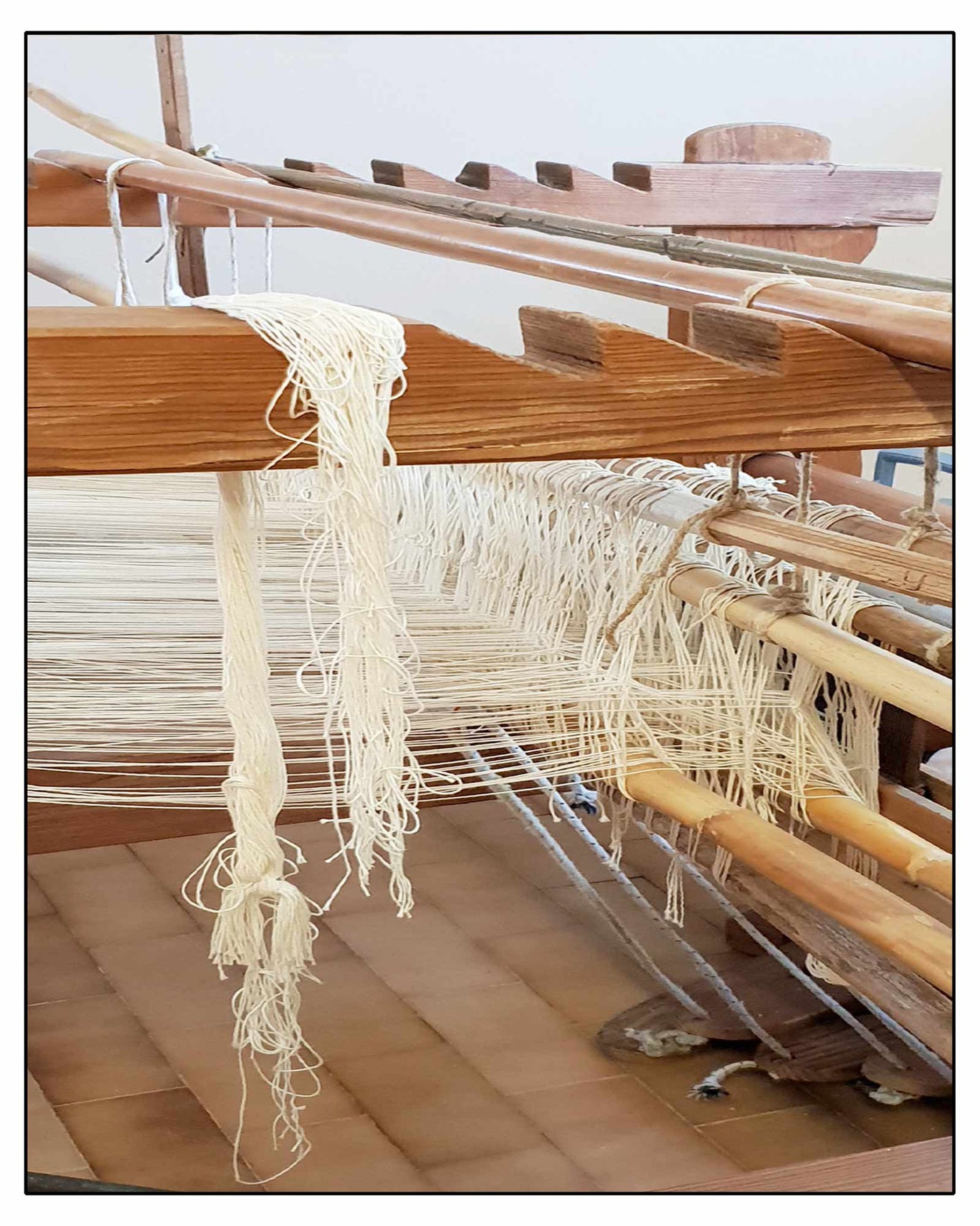 Close-up of a loom with threads and wooden beams where ANTONELLO TEDDE fabrics are made 