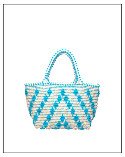Woven handbag with blue diamond pattern and pom-pom details on a white background. Celvia Medium Torquoise Tote Bag is handwoven, a reimagined classic that marks the return of the beloved rombetti (Multiple Diamonds) pattern in a fresh, contemporary silhouette
