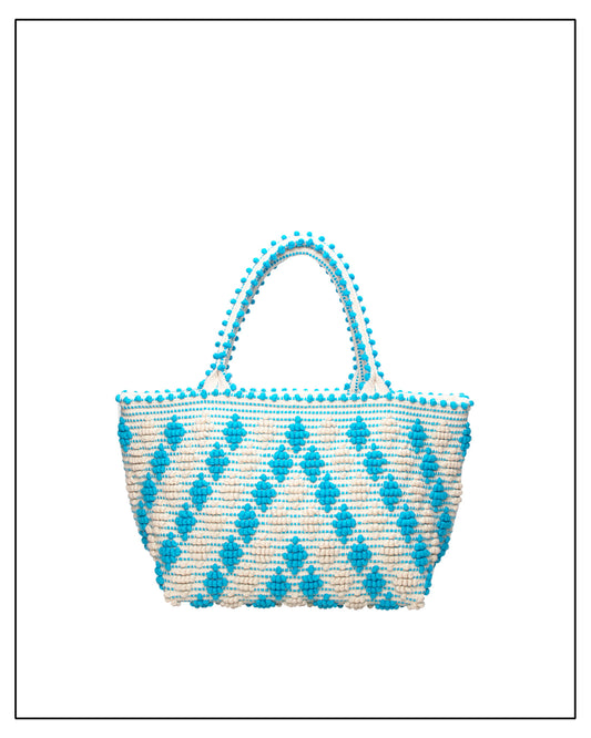 Woven handbag with blue diamond pattern and pom-pom details on a white background. Celvia Medium Torquoise Tote Bag is handwoven, a reimagined classic that marks the return of the beloved rombetti (Multiple Diamonds) pattern in a fresh, contemporary silhouette