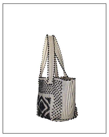 Side view of an Antonello Tedde Pula Medium Tote Bag is handwoven in Sardinia with black and golden yarn, a diamond pattern, and a practical flap pocket. 