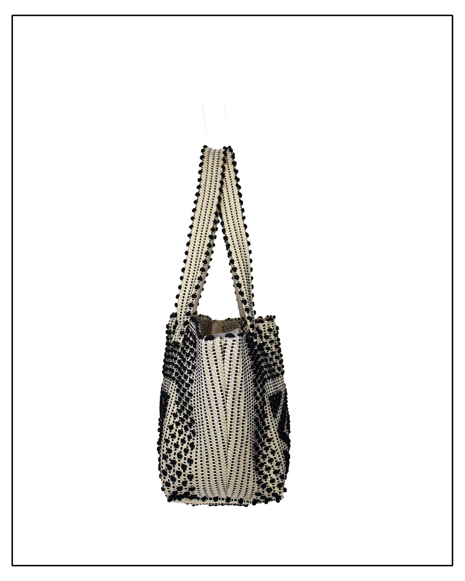 Side view of an Antonello Tedde Pula Medium Tote Bag is handwoven in Sardinia with black and golden yarn, a diamond pattern, and a practical flap pocket. 