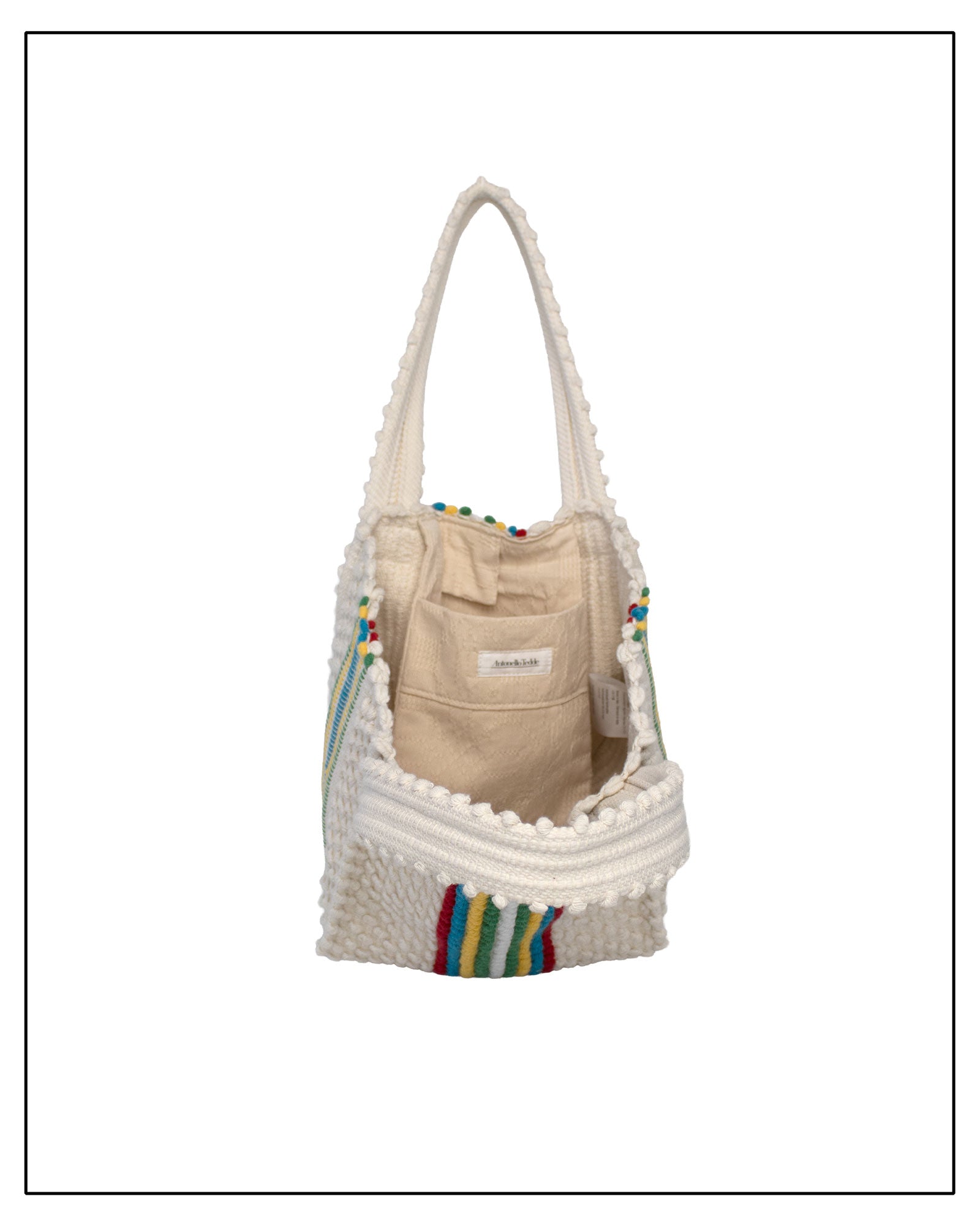 Beige bag with colourful accents inside a textured white bag on a white background.Inside view of ANTONELLO TEDDE Cream bag with colourful stripes on a white background - Pula Medium Tote Bag, a reimagined classic that marks the return of the beloved striscie (stripes) pattern in a fresh, contemporary silhouette.