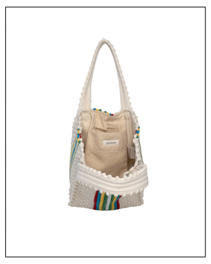 Beige bag with colourful accents inside a textured white bag on a white background.Inside view of ANTONELLO TEDDE Cream bag with colourful stripes on a white background - Pula Medium Tote Bag, a reimagined classic that marks the return of the beloved striscie (stripes) pattern in a fresh, contemporary silhouette.