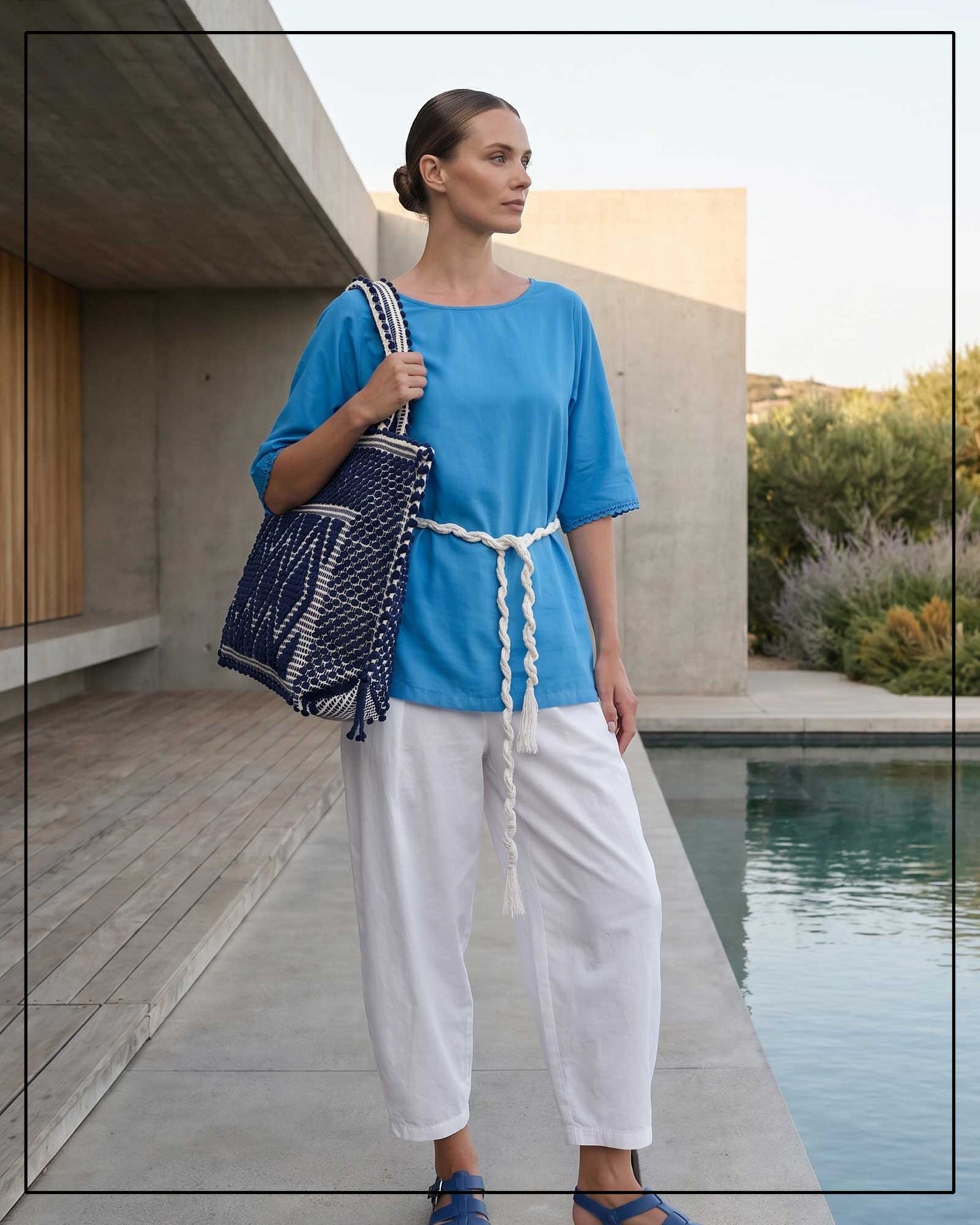 A woman in a blue top and white pants holding a blue and white bag by a poolside. All by Antonello Tedde