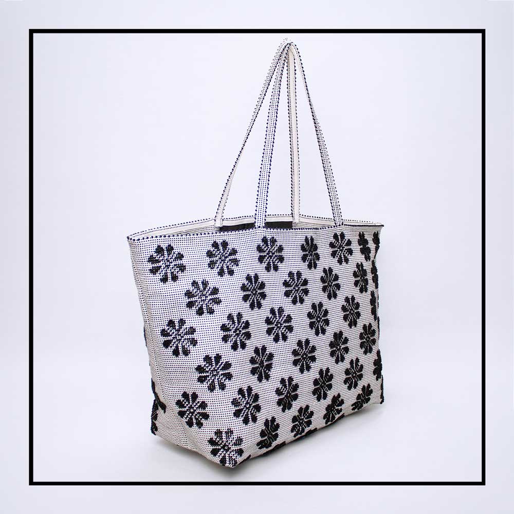 Side view of a black and white tote bag with a daisies pattern. Main view of our Sustainable tote - summer bag - luxury handbag - handwoven made in Italy by hand  - timeless individualistic fashion • eco-friendly fashion • socially responsible, lasting fashion.