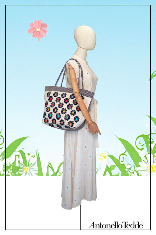 On Model  view of a black and white tote bag with a daisies pattern. Main view of our Sustainable tote - summer bag - luxury handbag - handwoven made in Italy by hand  - timeless individualistic fashion • eco-friendly fashion • socially responsible, lasting fashion.