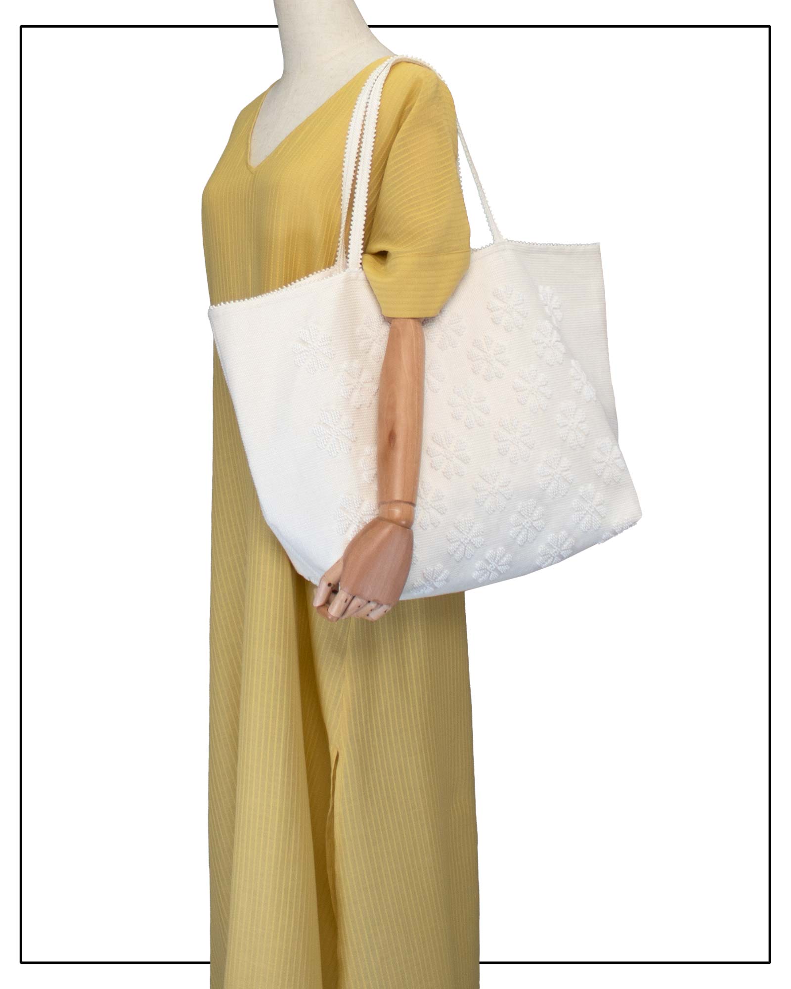 Mannequin wearing a mustard yellow outfit with a handwoven cream tote bag, all by Antonello Tedde