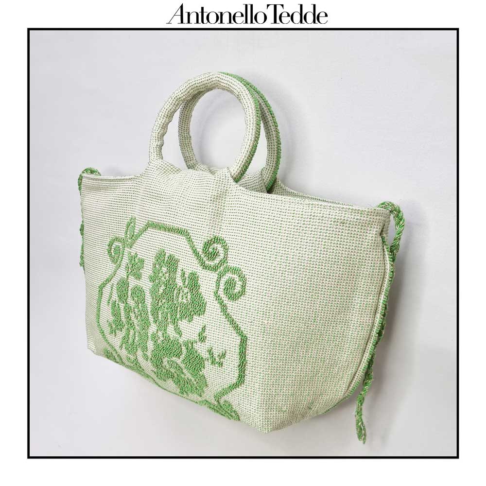 Side view of the handwoven green Faona tote bag with a small pibiones flower bouquet pattern and golden thread, which was crafted from regenerated cotton by Sardinian artisans.