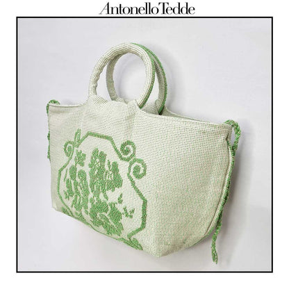 Side view of the handwoven green Faona tote bag with a small pibiones flower bouquet pattern and golden thread, which was crafted from regenerated cotton by Sardinian artisans.