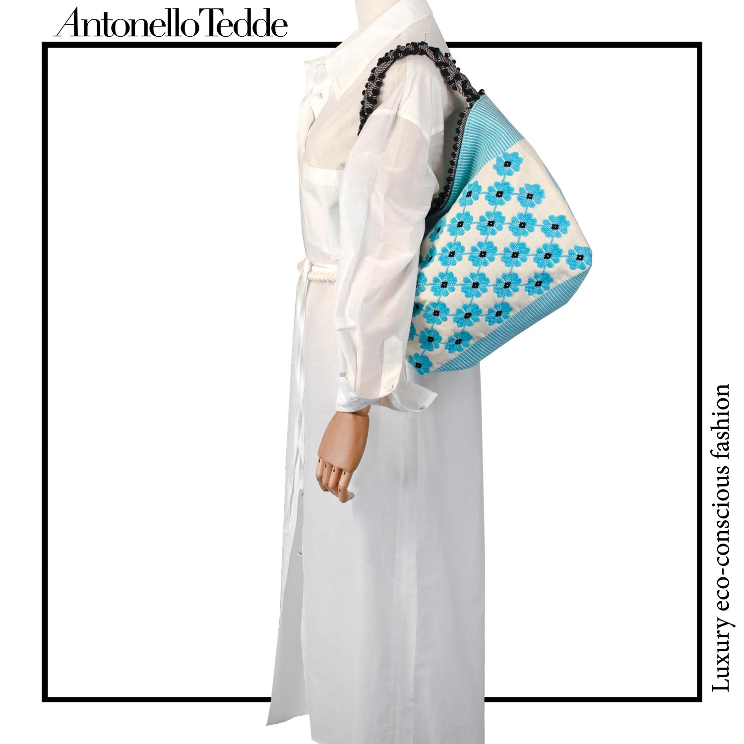 Mannequin view of a turquoise, black and white tote bag with a daisy pattern. Main view of our Sustainable tote - summer bag - luxury handbag - handwoven made in Italy by hand  - timeless individualistic fashion • eco-friendly fashion • socially responsible, lasting fashion.