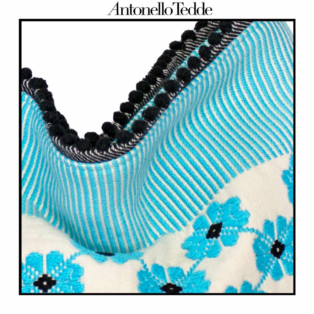 Close-up of a fabric with blue floral pattern and black accents, branded 'Antonello Tedde'.