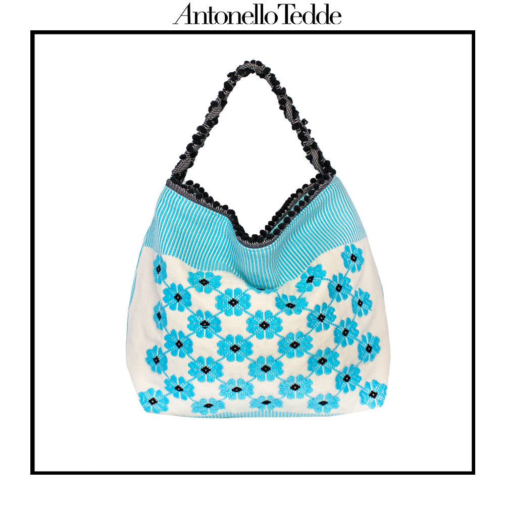 Front view of a turquoise, black and white tote bag with a daisy pattern. Main view of our Sustainable tote - summer bag - luxury handbag - handwoven made in Italy by hand  - timeless individualistic fashion • eco-friendly fashion • socially responsible, lasting fashion.