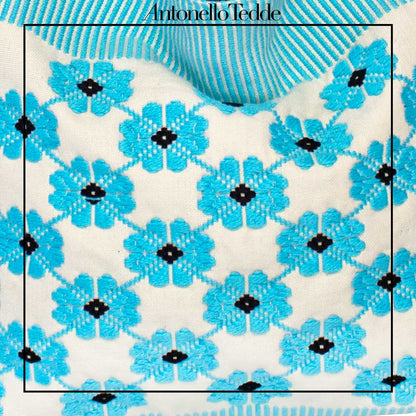 Close-up of a patterned fabric with blue flowers and black centers, branded 'Antonello Tedde'. view of a turquoise, black and white tote bag with a daisy pattern. Main view of our Sustainable tote - summer bag - luxury handbag - handwoven made in Italy by hand  - timeless individualistic fashion • eco-friendly fashion • socially responsible, lasting fashion.