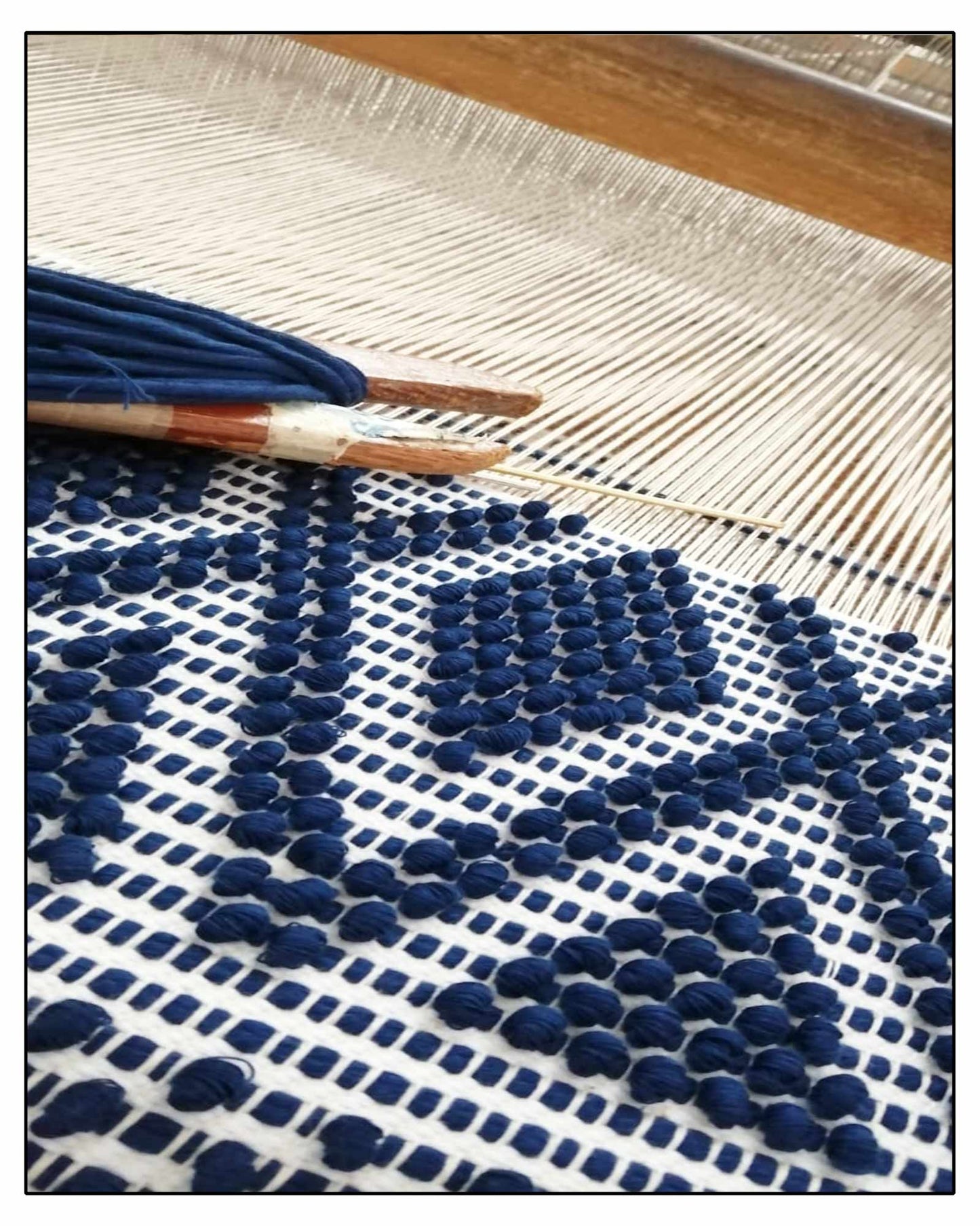 Textile made for ANTONELLO TEDDE BAGS  with blue pom-poms on a wooden loom 