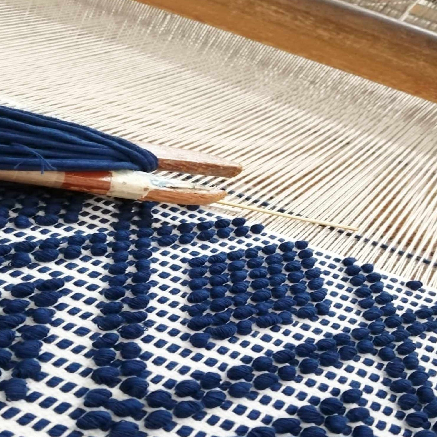 Textile made for ANTONELLO TEDDE BAGS  with blue pom-poms on a wooden loom 