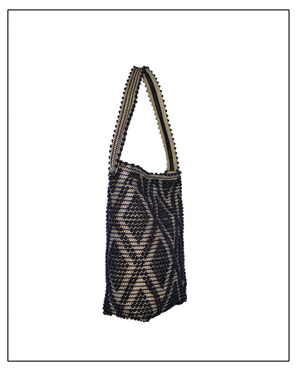 Side view of an Antonello Tedde Bultei Rombi shoulder bucket bag, handwoven in Sardinia from black cotton with a shimmering golden viscose diamond pattern. 