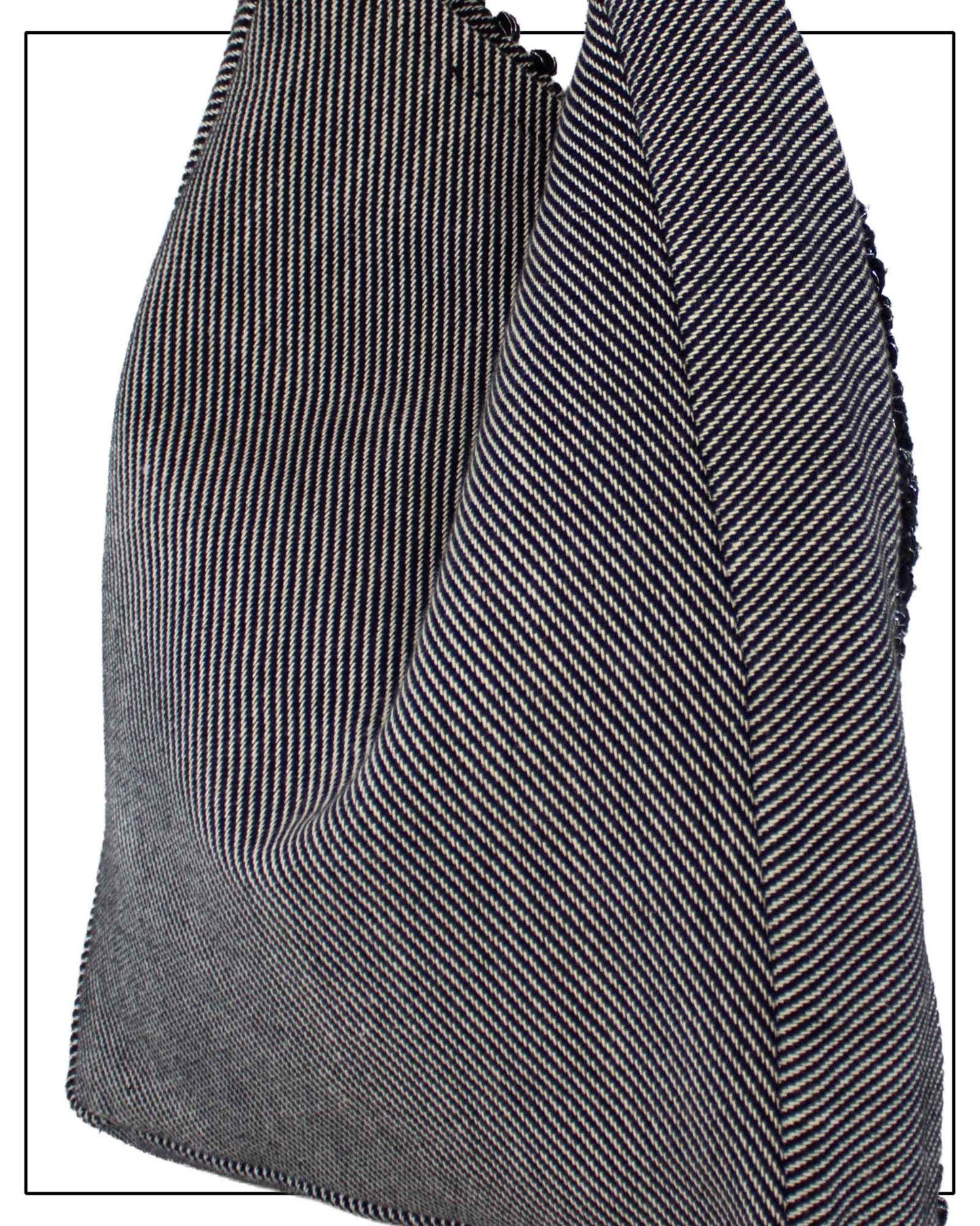 A close-up of the back view of Antonello Tedde Bultei's handwoven tote bag in black cotton with subtle silver highlights and a textured woven front panel, handcrafted in Sardinia. and white herringbone pattern, showing the texture and fold details against a white background.