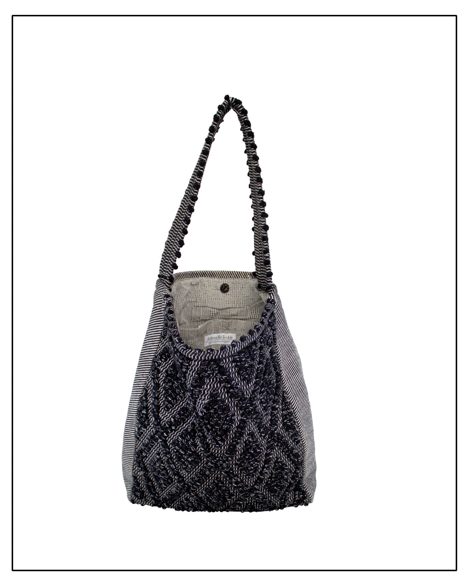 Lining view of Antonello Tedde Bultei handwoven tote bag in black cotton with subtle silver highlights and textured woven front panel, handcrafted in Sardinia.