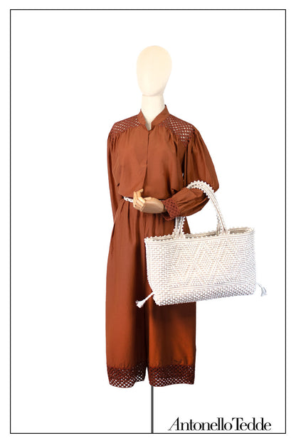 Mannequin wearing a brown outfit holding a white handwoven handbag with 'Antonello Tedde' branding. Medium tote bag cream base chestnut Ethical and Sustainable Handbags.  The best eco luxury bags and accessories brand. 