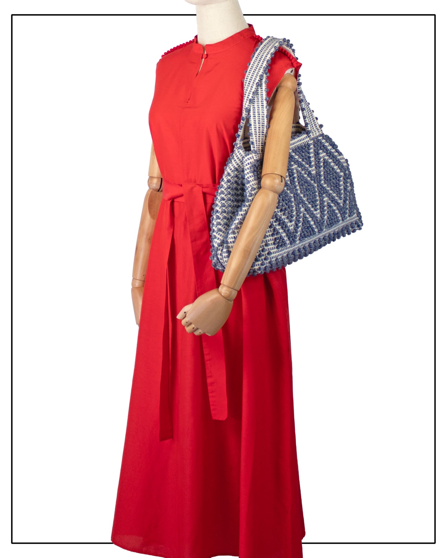 Red dress with a patterned tote on a mannequin against a white background -  view of Antonello Tedde Celvia Medium Tote Bag in handwoven melange blue cotton with large diamond rombi pattern