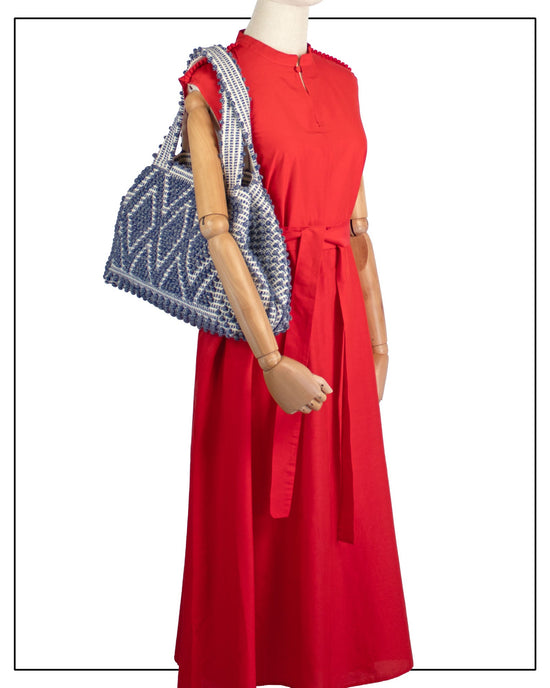 Red dress with a patterned tote on a mannequin against a white background -  view of Antonello Tedde Celvia Medium Tote Bag in handwoven melange blue cotton with large diamond rombi pattern