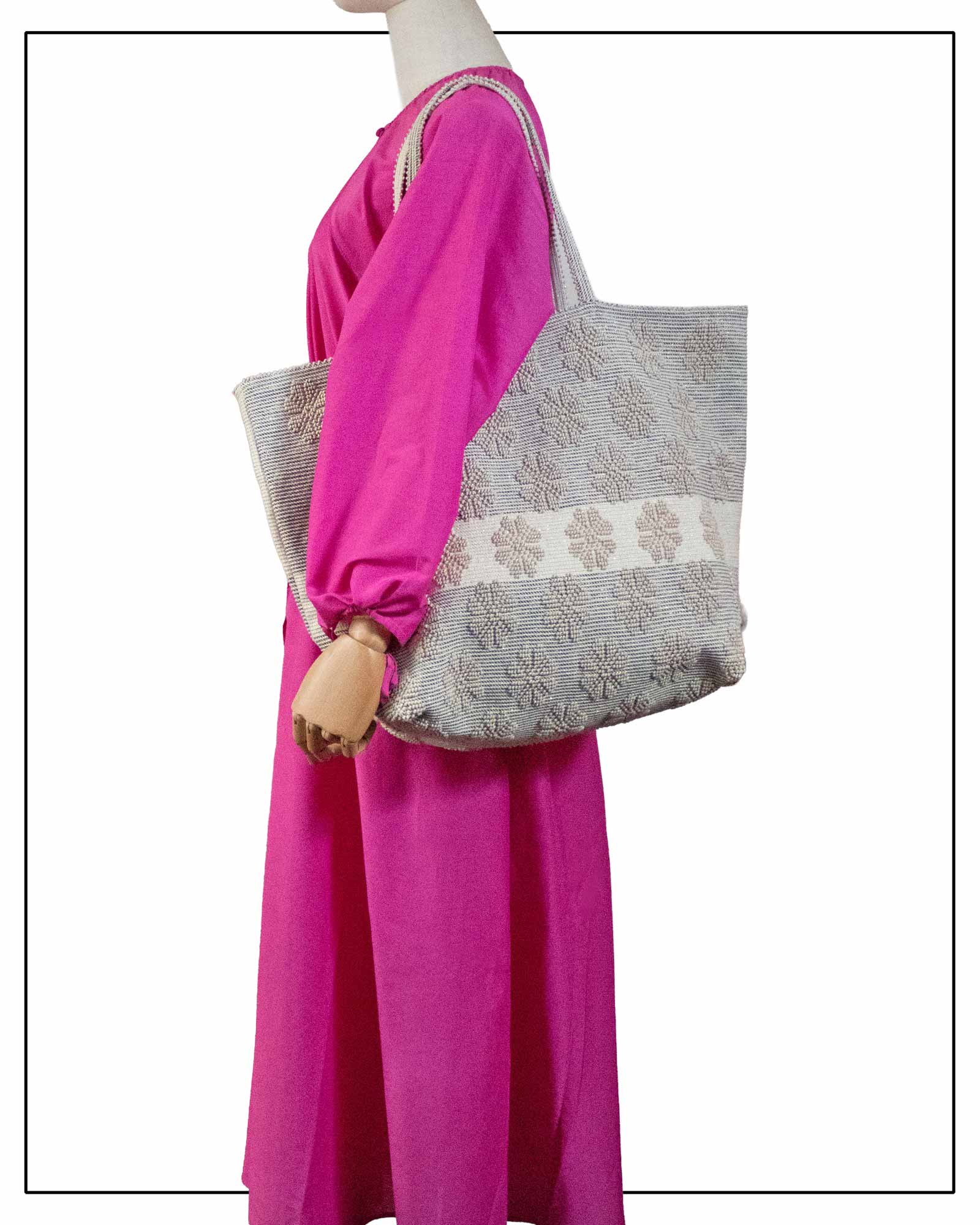 Mannequin in a fuchsia dress holding a handwoven large tote bag with a daisy pattern in beige and black, all by Antonello Tedde