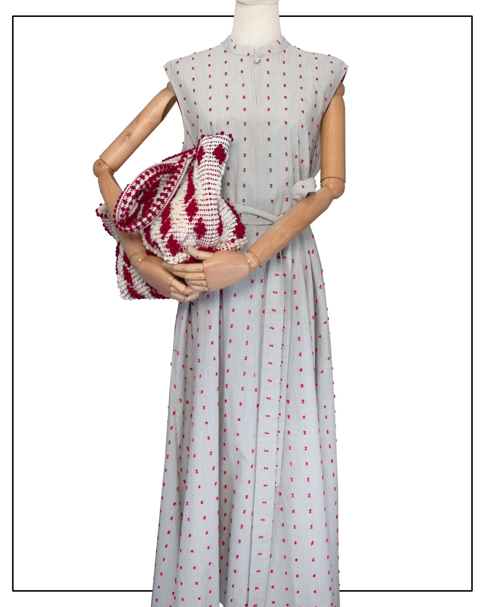 Mannequin wearing an Antonello Tedde long light grey dress with red patterns, holding a matching red-and-white patterned bag. Red-and-white patterned handbag on a white background. Celvia Medium Red and Cream Tote Bag is handwoven, a reimagined classic that marks the return of the beloved rombetti (Multiple Diamonds) pattern in a fresh, contemporary silhouette