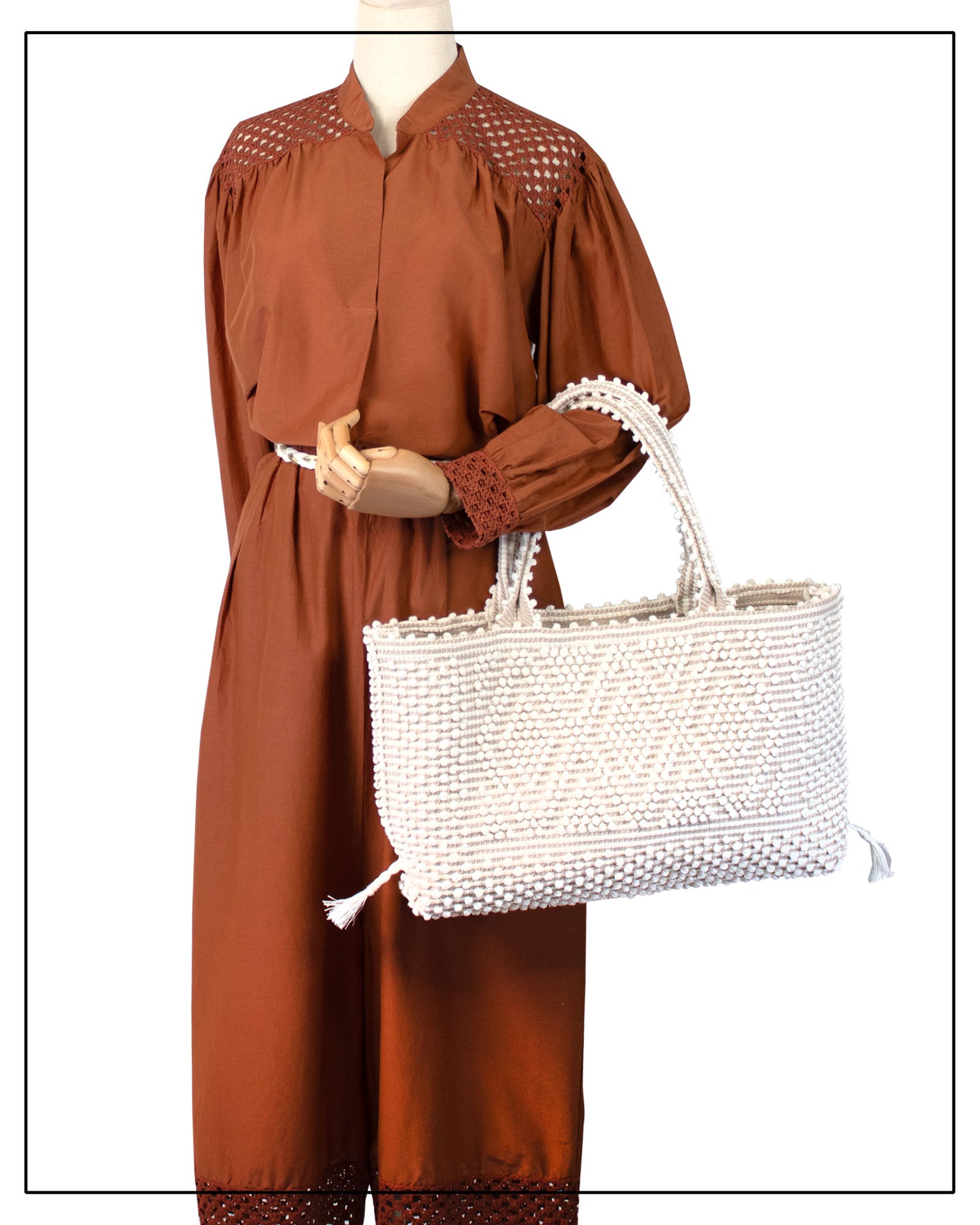 Mannequin wearing a brown dress, holding a white woven handbag on a white background - Medium tote bag with a cream base and chestnut details. Ethical and Sustainable Handbags.  The best eco luxury bags and accessories brand. 