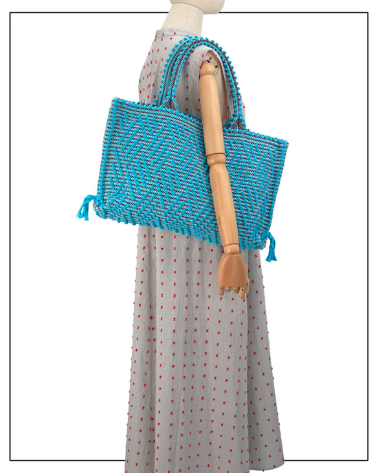 Blue woven bag on a mannequin with a handwoven black and turquoise tote with geometric pattern made in Italy by hand • timeless individualistic fashion • eco-friendly fashion • socially responsible, lasting fashion.