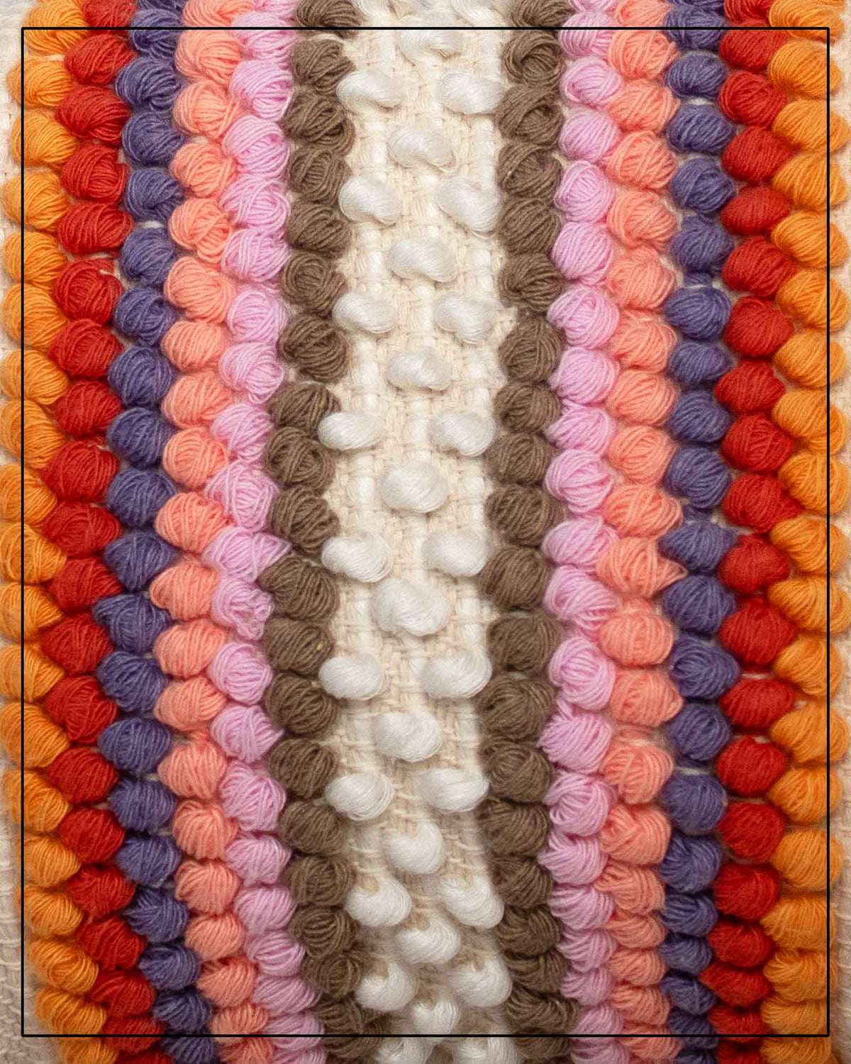 View of Antonello Tedde Suni Fire crossbody bag fabric, handwoven in Sardinia in cream linen and cotton with colourful raised stripes and braided shoulder strap.A close-up of a colourful knitted textile with vertical stripes of textured yarn in cream, taupe, pink, peach, purple, red, orange, and yellow.