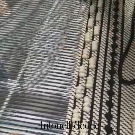 Close-up of a loom with threads and wooden beams where ANTONELLO TEDDE fabrics are made 